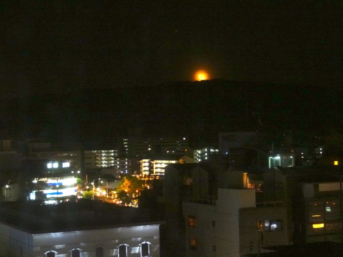 Peaking over the hills toward Yamashina in the east, the moon appears yellow as it rises over Kyoto during the Golden Week holiday.