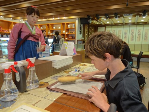 Alex makes a wood block ink print at the airport in Seoul.