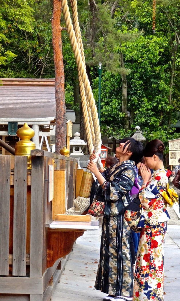 Buddhist stop to make an offering and ring a bell attached to a long cotton rope in front of one of Kyoto's many temples.